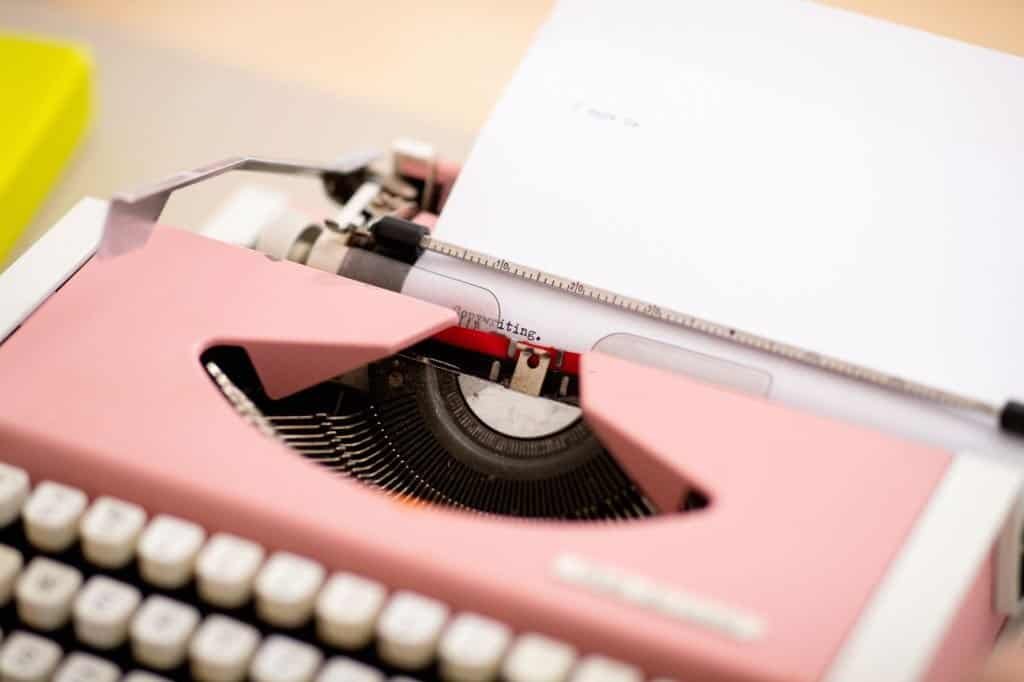 Word "Copywriting" and full stop, typed out on a paper in pink typewriter